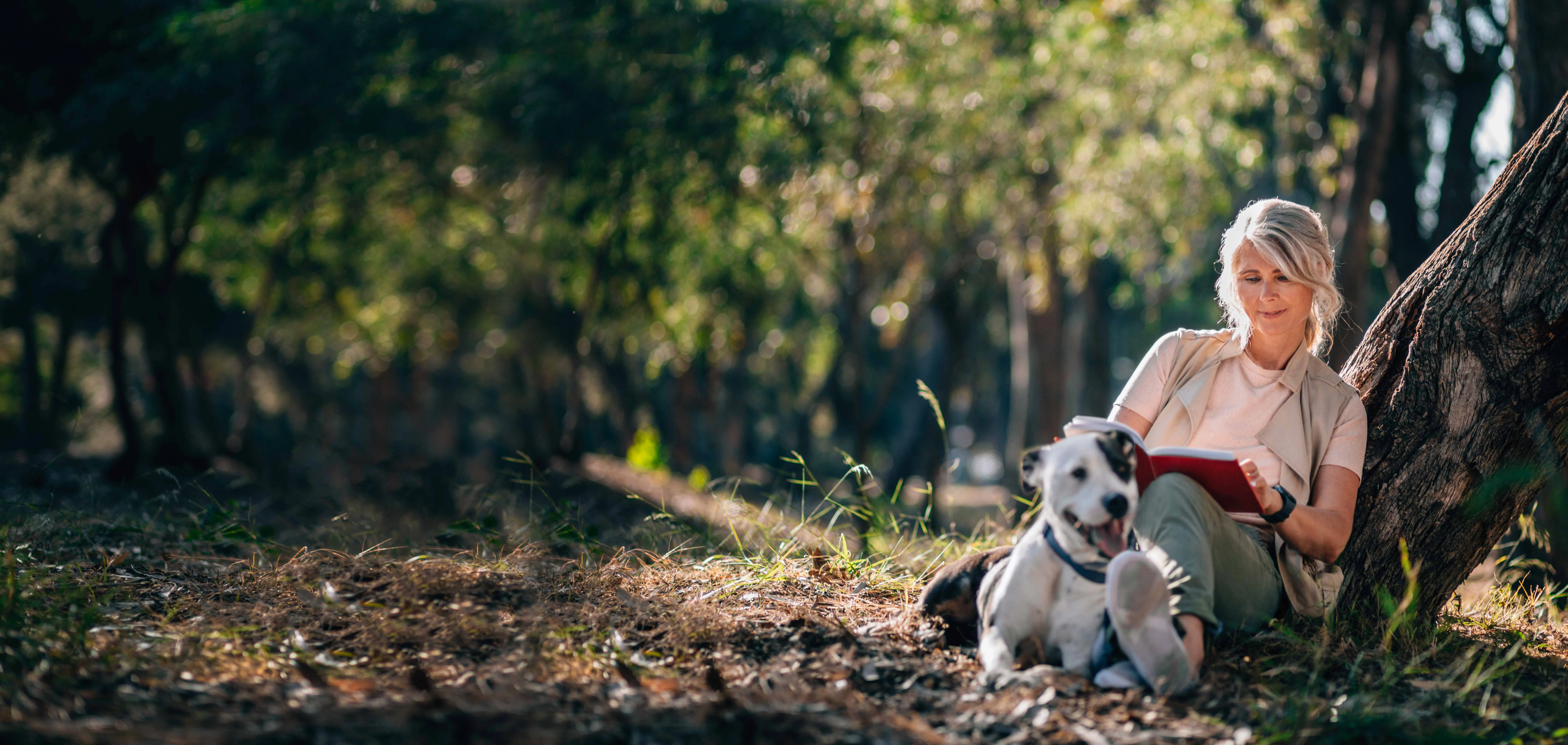 uma pessoa sentada na floresta com um cachorro