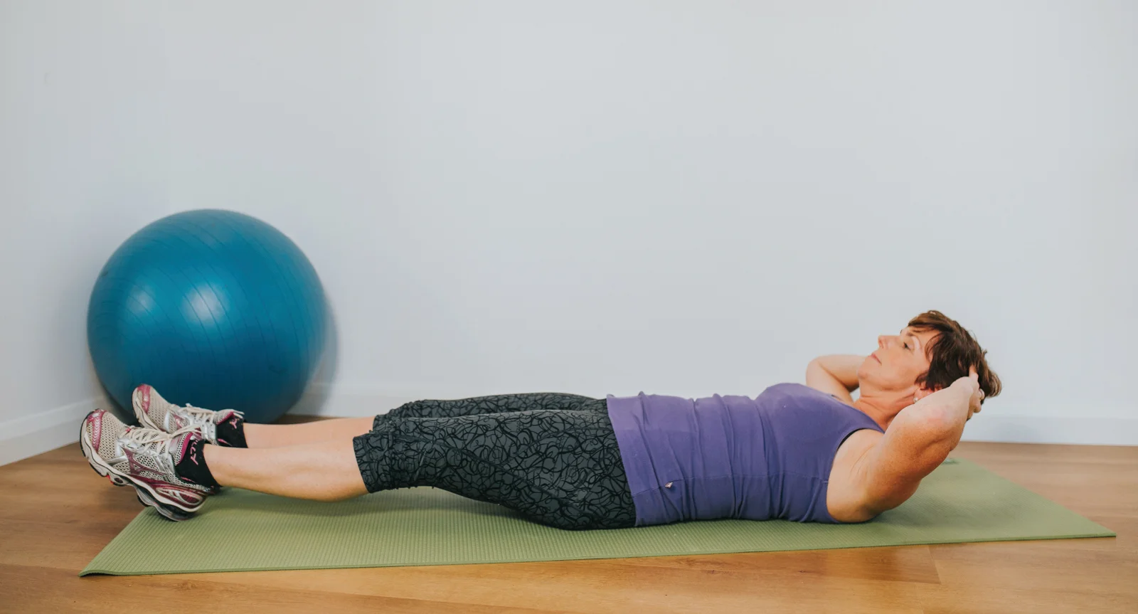 une personne allongée sur un tapis de yoga avec une balle bleue