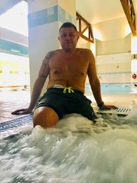 man living with a stoma posing at a swimming pool