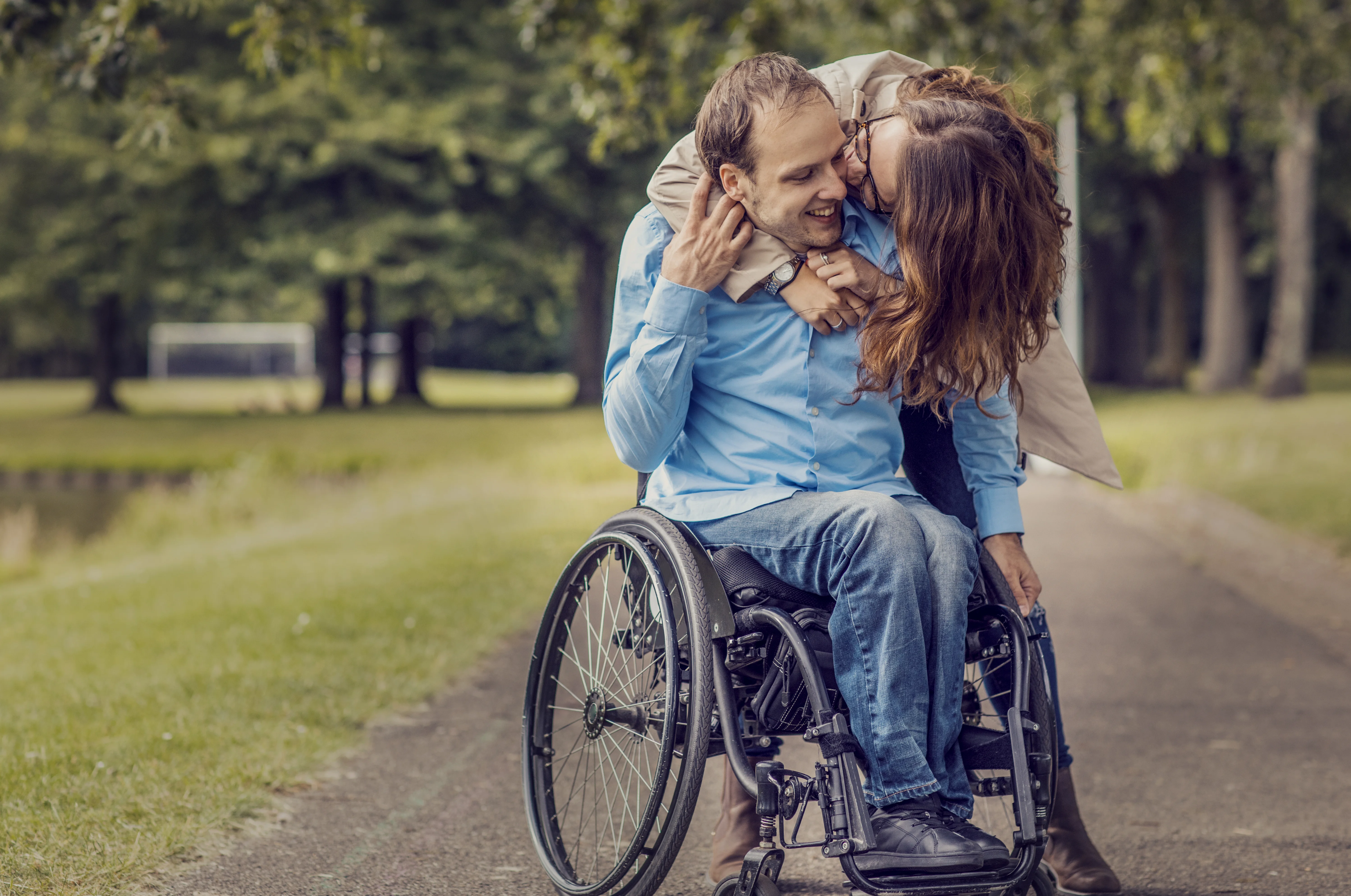 Un homme et une femme s’embrassent dans un fauteuil roulant